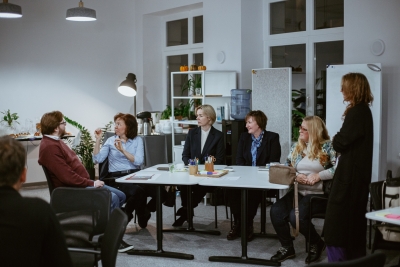 Dalībnieku grupa diskutē pie galda darbnīcas laikā.