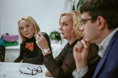 Darbnīcas dalībniece runā grupas diskusijā, turot rokā pildspalvu.